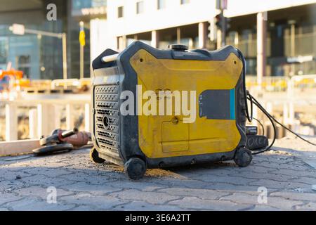 Centrale elettrica portatile industriale e attrezzature da costruzione sul marciapiede della città per l'elettricità fuori rete durante lo sviluppo urbano e la manutenzione dei servizi pubblici Foto Stock