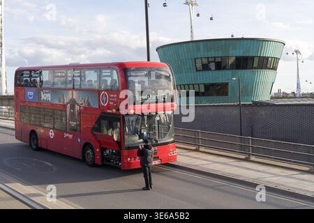 LONDRA, Regno Unito - 5 aprile 2026: Un autista di autobus della Route 129 che documenta un guasto meccanico su un autobus a due piani Transport for London (TfL). Il pannello di manutenzione laterale è aperto, esponendo i componenti interni del veicolo nella "zona di guasto" sotto la cabina operatore. L'incidente si è verificato durante l'avvicinamento al Silvertown Tunnel North Portal. Sullo sfondo, la sala di controllo rivestita di turchese e la funivia IFS Cloud illustrano l'intersezione tra vecchia e nuova infrastruttura di trasporto durante un tranquillo periodo della domenica di Pasqua. Credito: xiu bao/Alamy Live News Foto Stock