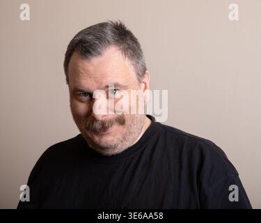 L'uomo di mezza età in camicia nera sorride calorosamente Foto Stock