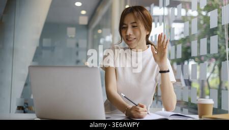 Giovane università femminile prendendo appunti e utilizzando l'evidenziatore. Studente focalizzato in aula online. Concetto di istruzione autentica Foto Stock