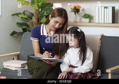 Una madre e una figlia condividono un momento di gioia mentre si impegnano in attività educative, promuovendo un ambiente di supporto Foto Stock