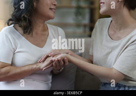 La donna asiatica anziana felice e la sua figlia adulta stanno coccolando sul divano Foto Stock