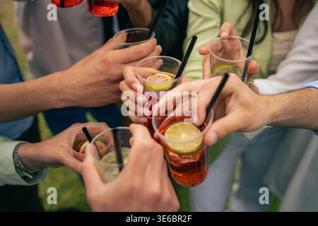 Immagine ravvicinata di un gruppo di mani che alzano le bevande, simboleggiano una festa o un incontro. Foto Stock