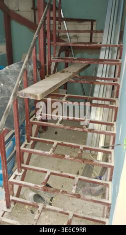 È in corso una struttura di scala in metallo grezzo, circondata da materiali di costruzione e pareti incompiute Foto Stock