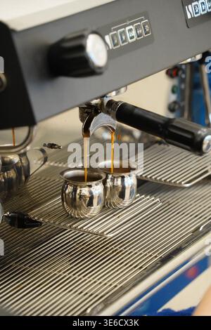 Doppio espresso erogato dalla macchina per il caffè in piccole caraffe in acciaio Foto Stock