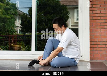 Pronto al mattino alla porta, si siede accanto al patio e indossa calzini prima di uscire. Un inizio tranquillo e organizzato che definisce il tono della giornata. Foto Stock