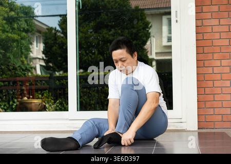 Pronto al mattino alla porta, si siede accanto al patio e indossa calzini prima di uscire. Un inizio tranquillo e organizzato che definisce il tono della giornata. Foto Stock