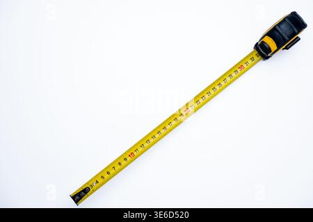 Nastro di misurazione esteso diagonalmente su uno sfondo chiaro e pulito con spazio di copia, ideale per progetti edili, fai da te o concetti di misurazione. Foto Stock