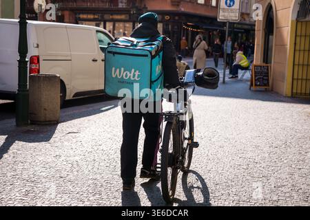 PRAGA, REPUBBLICA CECA. 28 marzo 2025. Corriere per la consegna di cibo con una bicicletta su una strada della città: Una vista sul retro di un corriere partner Wolt che porta un blu Foto Stock