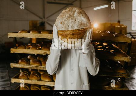 Orgoglioso dei suoi prodotti da forno. Bel giovane in grembiule con cesto con prodotti da forno e sorridendo mentre si trova in una panetteria Foto Stock