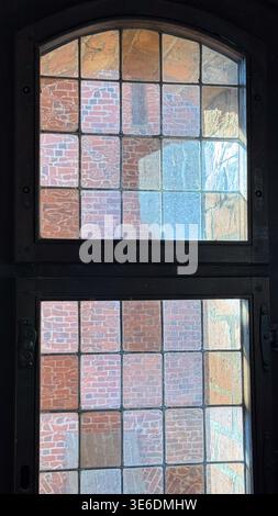 Vecchia finestra con piccoli pannelli di vetro e cornice in legno all'interno del castello di Malbork in Polonia che mostra pareti in mattoni all'esterno. Architettura, interni e edifici storici Foto Stock