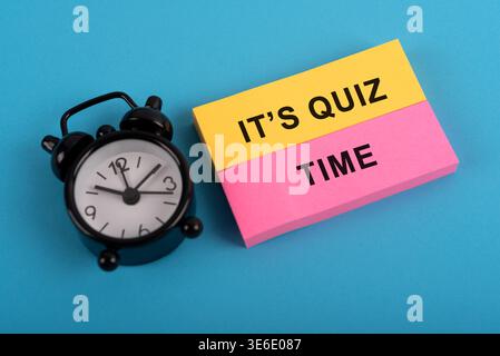 Sveglia e nota in carta colorata con testo è ora del quiz Foto Stock
