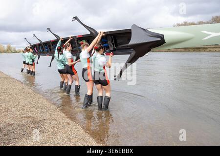 Squadra di canottaggio femminile dell'università di Cambridge che trasporta la barca nel Tamigi a Putney prima della gara di barche Foto Stock