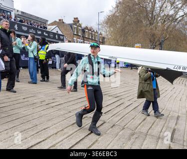 Cambridge University cox Matt Moran con il team Womens Boat Race che trasporta la barca sul tamigi per la gara Foto Stock
