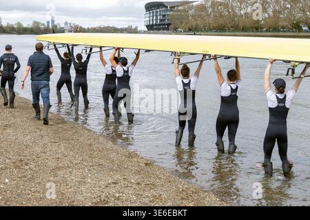 Oxford University Boat Race le donne vogano sollevando la barca cranica sopra le teste prima di scendere al fiume Tamigi a Putney prima della gara di barche Foto Stock