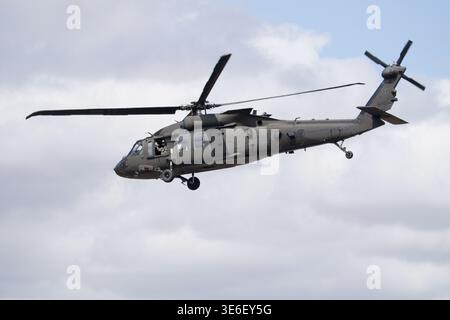 Un elicottero variante Black Hawk delle forze armate svedesi, con un membro dell'equipaggio visibile, viene catturato in volo contro un cielo parzialmente nuvoloso. Foto Stock