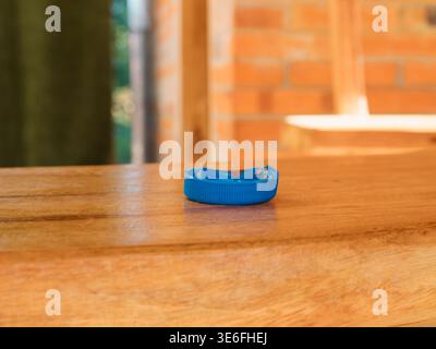 Un coperchio in plastica blu poggia su una superficie in legno. Lo sfondo mostra un muro di mattoni sfocato. Questa immagine è adatta a temi legati all'ambiente, Foto Stock