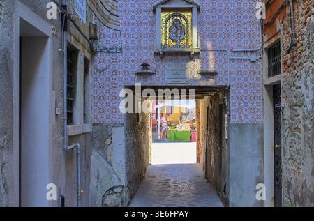 Venezia, Italia - 24 maggio 2024: Vista pittoresca di una stradina che conduce al vivace mercato del pesce di Chioggia, Italia, che mostra la vita locale e la comm Foto Stock
