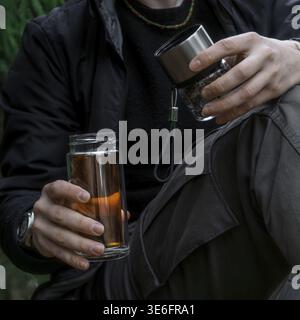 Una persona trova gioia nel sorseggiare bevande calde mentre è circondata dalla bellezza mozzafiato della natura all'aperto Foto Stock