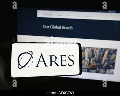 Stoccarda, Germania - 12-08-2024: Persona che possiede uno smartphone con il logo della società di investimento statunitense Ares Management Corporation davanti al sito web. Messa a fuoco o Foto Stock