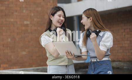 Bella giovane studentessa asiatica con amici all'aperto. Studente universitario che lavora nel campus universitario Foto Stock
