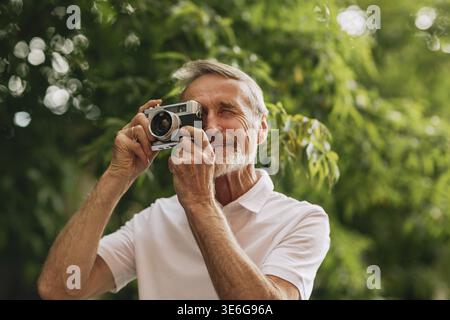Senior uomo fare fotografie su pellicola fotocamera mentre passeggiate all'aperto Foto Stock