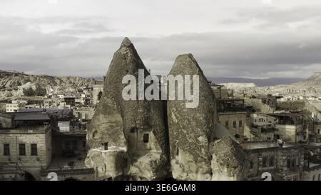 Antiche abitazioni in pietra scolpite dal tufo in Cappadocia, Turchia. Azione. Vista aerea di una natura insolita, formazioni rocciose, città e cielo nuvoloso Foto Stock