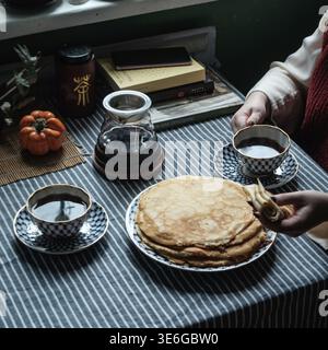 Una deliziosa colazione calda con soffici pancake, caffè ricco e un tocco affascinante di arredamento autunnale Foto Stock