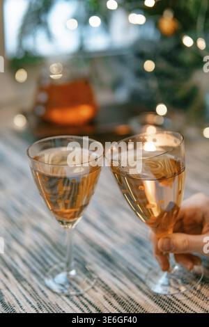 In un ambiente accogliente e scintillante, un brindisi gioioso è fatto con eleganti bicchieri pieni di spumante Foto Stock