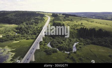 Vista aerea sulla strada di montagna che attraversa il paesaggio della foresta. Bellissimo paesaggio con strada di montagna con auto e sfondo forestale. Tramonto i Foto Stock