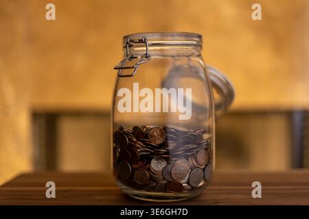 Monete in vaso aperto per muratori con illuminazione calda: Risparmio e budget Foto Stock