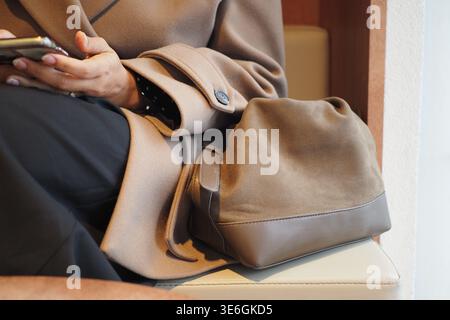 donna che controlla il telefono seduto con la borsa Foto Stock