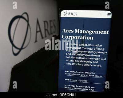 Stoccarda, Germania - 08-12-2024: Persona che detiene il cellulare con pagina web della società di investimento statunitense Ares Management Corporation davanti al logo. Concentrati su Foto Stock
