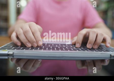 Mano di donna che utilizza un computer portatile per lavorare, scrivendo a casa e scorrendo, seduto sul tavolo, primo piano di giovani donne mano Foto Stock
