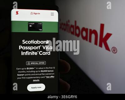 Stoccarda, Germania - 12-08-2024: Persona che possiede uno smartphone con pagina web della società finanziaria Bank of Nova Scotia (Scotiabank) davanti al logo. Concentrati Foto Stock