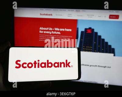 Stoccarda, Germania - 12-08-2024: Persona con smartphone con logo della società finanziaria Bank of Nova Scotia (Scotiabank) davanti al sito web. Concentrati Foto Stock