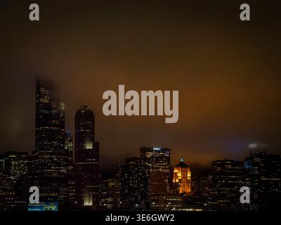 Foggy skyline di Chicago di notte con nuvole arancioni e grattacieli illuminati sul paesaggio urbano del centro Foto Stock