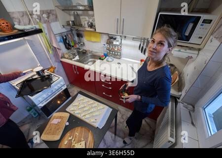 Due amiche di mezza età cucinano croissant di pasta sfoglia insieme come uno mette il vassoio nel forno Foto Stock