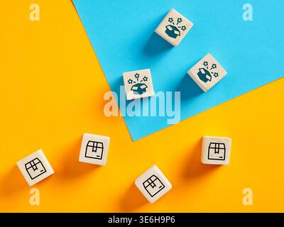 Cubi di legno con icone e stelle che simboleggiano l'emozione di aprire una consegna, su uno sfondo giallo e blu vibrante Foto Stock