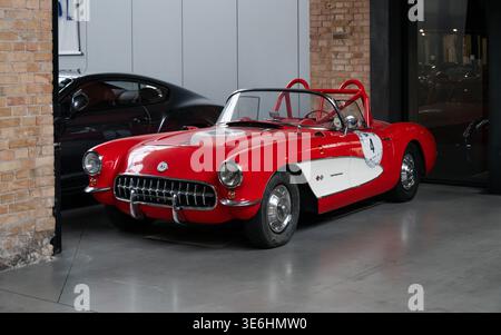 Auto da corsa Corvette C1 classica rossa e bianca nel garage. Vista frontale di tre quarti della Chevrolet Corvette Roadster 1957 con roll bar rosso. Foto Stock
