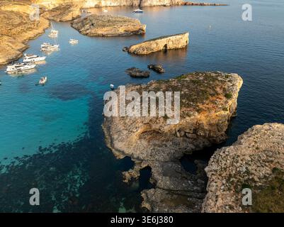 Vista aerea delle acque turchesi incontra scogliere aspre e barche ancorate nella Laguna Blu, Comino, Malta. Foto Stock