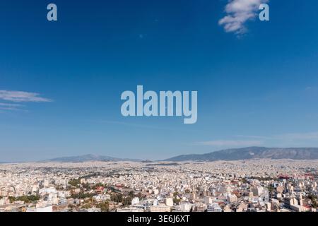 Ampia vista panoramica della città di Atene e delle montagne circostanti sotto il cielo azzurro della Grecia Foto Stock