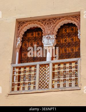 Doppia finestra moresca decorata con intricati stucchi e intagli in legno a Marrakech. Marocco Foto Stock