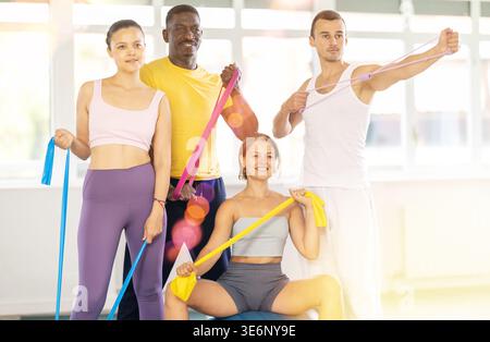Gruppo multietnico di allegri sportivi con attrezzature fitness in studio Foto Stock