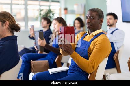 Un lavoratore maschio scatta una foto con il telefono cellulare o fotografa il codice QR sulla bacheca in classe Foto Stock