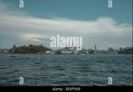 Vista delle navi della Royal Australian Navy a Garden Island e di una barca a vela sul porto di Sydney con ampio spazio per le copie nel cielo. Foto Stock