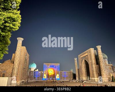 Vista notturna di Piazza Registan con madrasa illuminate e visitatori a Samarcanda, Uzbekistan. Foto Stock