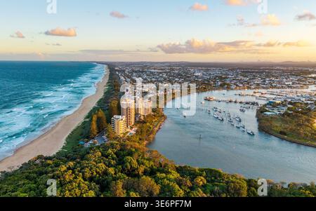 Una vista aerea cattura il fiume Mooloolah che incontra l'Oceano Pacifico vicino a Point Cartwright, Queensland, inondato dalla calda luce del tramonto. Foto Stock