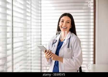 Medico sorridente in camice bianco in posa in clinica Foto Stock