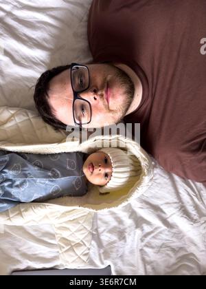 Padre e neonato riposano insieme sul letto Foto Stock